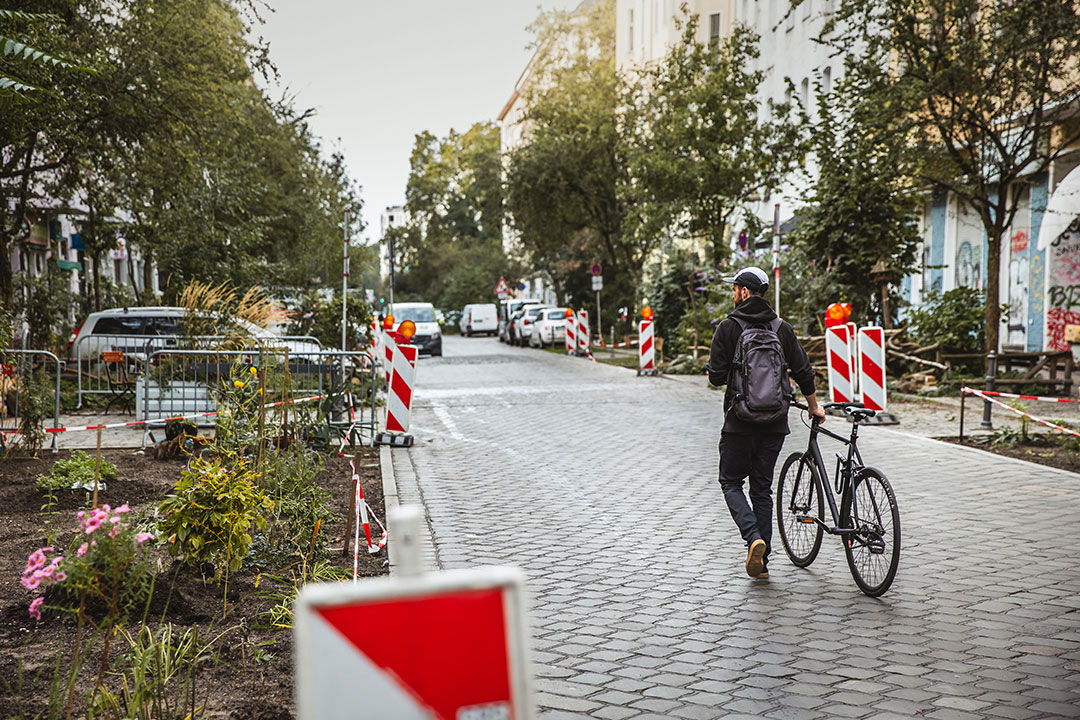 Ein Fahrradfahrer schiebt sein Rad durch eine autofreie Straße in Friedrichshain-Kreuzberg