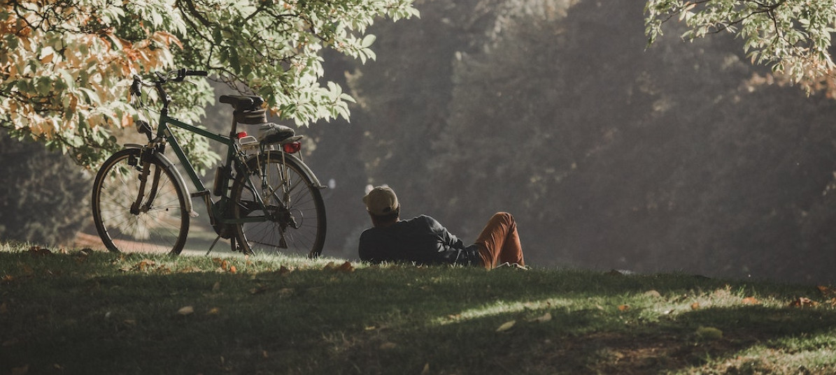 Mann liegt auf Wiese, Fahrrad steht neben ihm.
