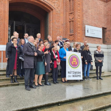 Die Gründer:innen, ehemalige Bürgermeisterin Franziska Giffey und andere halten das Logo des Netzwerk der Wärme in die Kamera vor dem roten Rathaus.