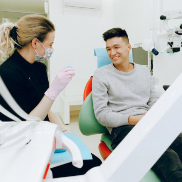 Zahnärztin zeigt Patient ein Objekts beide lachen.