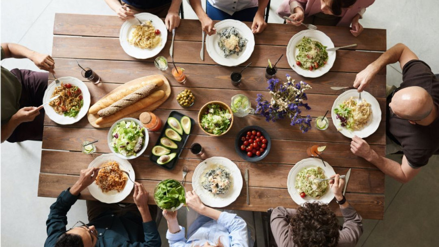 Dinner von oben, Tisch mit acht Personen und ihrem Essen