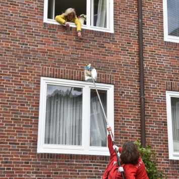 Care-Paket wird über das Fenster an Seniorin übergeben (Bild: Live To Love Germany Stiftung)