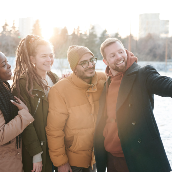 Vier Freund:innen machen ein Selfie in einem verschneiten Park