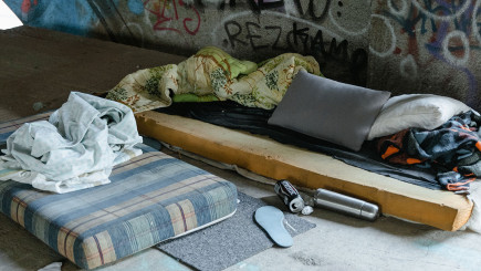 Matratzenlager von obdachlosen Menschen unter einer Brücke