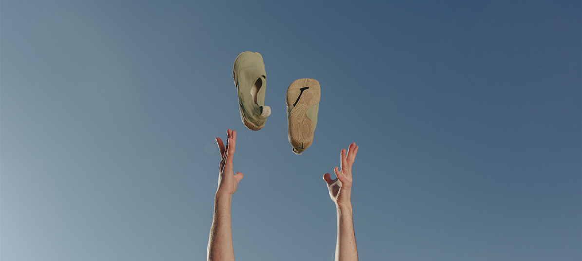Ein Paar Schuhe von Wildling Shoes werden in die Luft geworfen, dahinter blauer Himmel