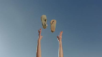 Ein Paar Schuhe von Wildling Shoes werden in die Luft geworfen, dahinter blauer Himmel