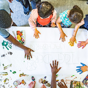 Kinder malen mit Fingerfarben gemeinsam ein Bild.