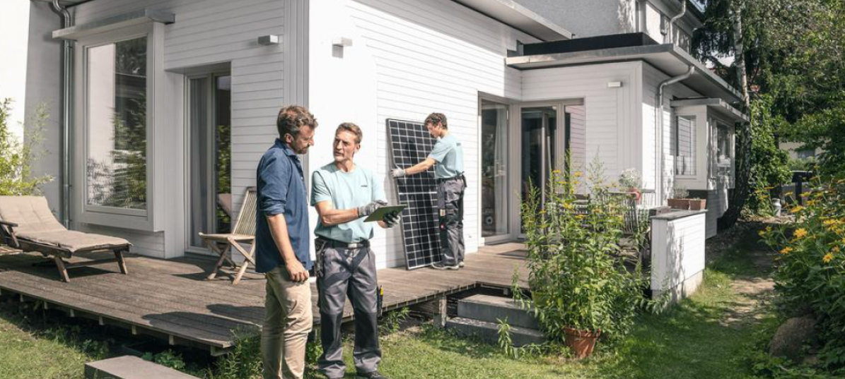 Ein Experte von zolar erklärt einem Eigenheimbesitzer im Garten die gleich stattfindende Installation seiner Solaranlage