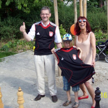 Günter Schütz, Leiter der Schachabteilung des FC Bayern schenkte zur Einweihung des gespendeten Spiels dem jüngsten Spieler ein T Shirt (Bild: "Mehr Platz zum Leben"