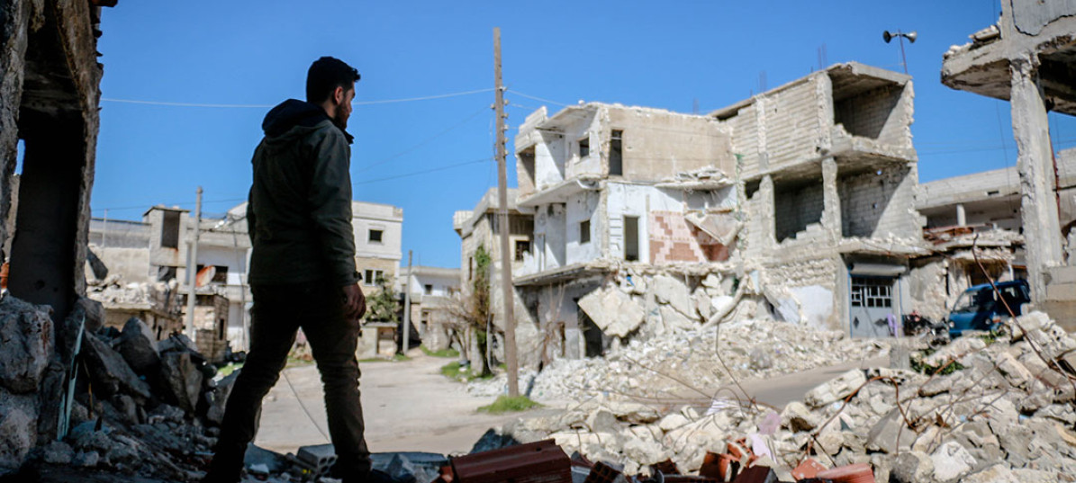 Mann steht in Syrien vor den Trümmern eines Wohngebäudes